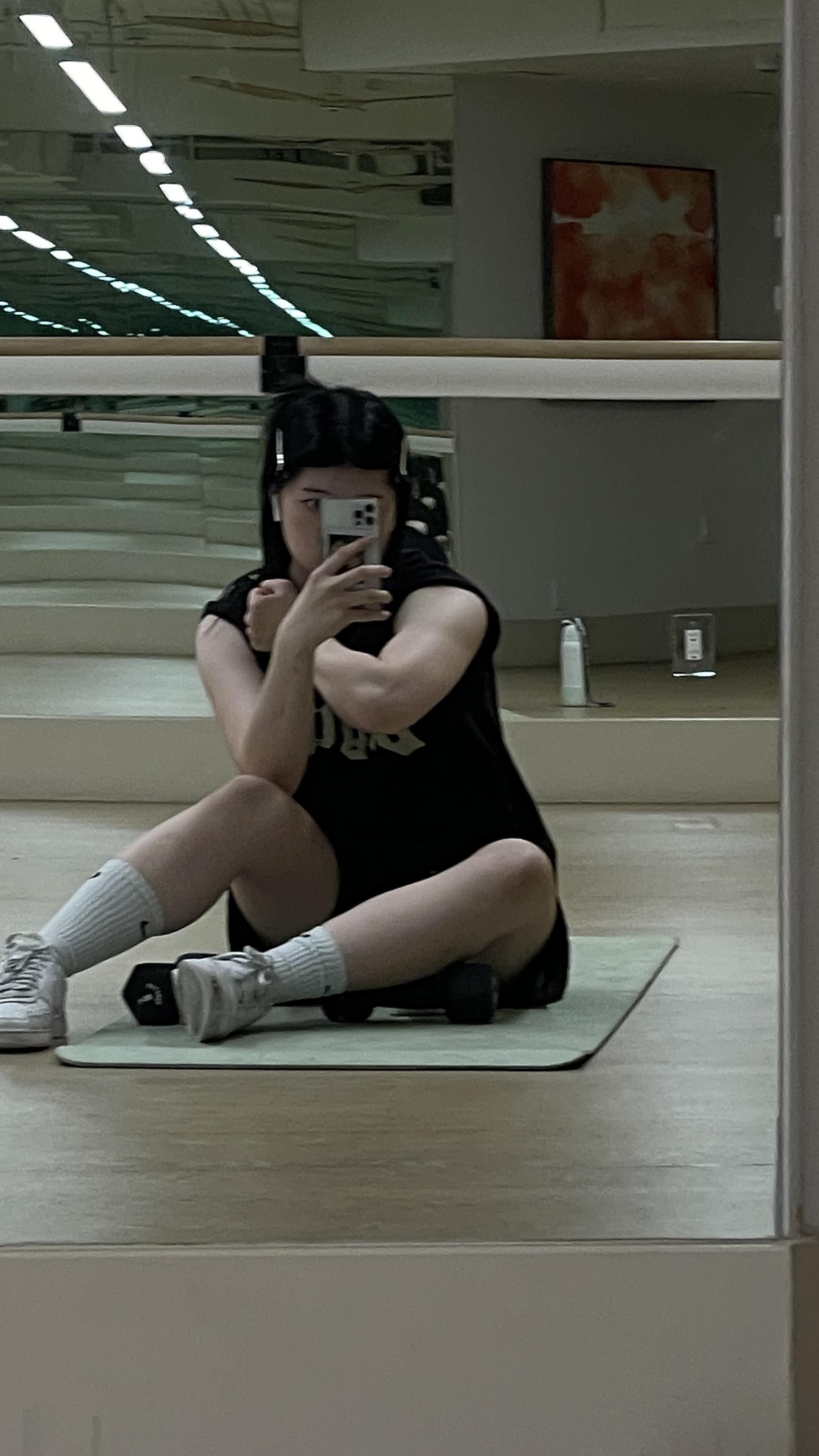 Mirror selfie of Natasha flexing arm at gym, with big arm muscle